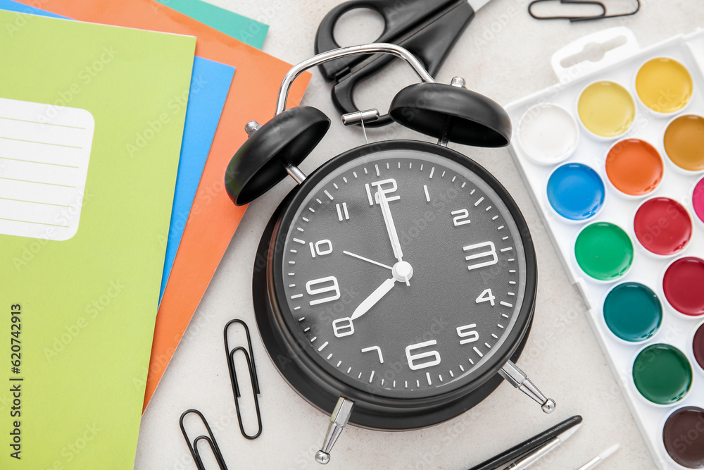 Alarm clock with different stationery on beige background