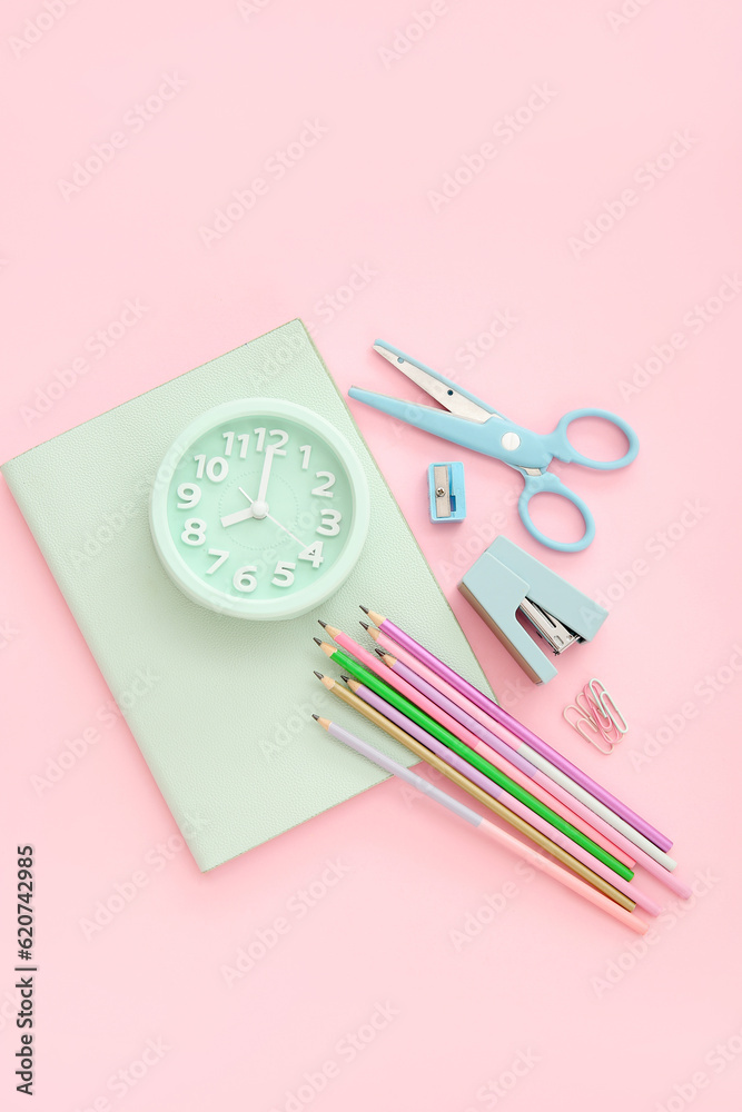 Alarm clock with different stationery on pink background