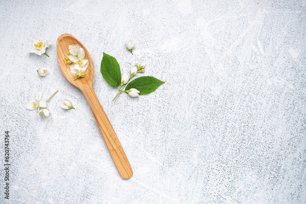 Wooden spoon with beautiful jasmine flowers on light background