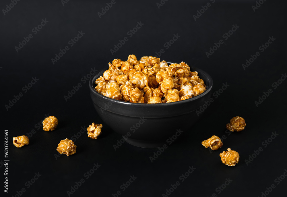 Bowl with tasty popcorn on black background