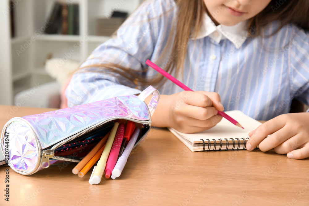 Little girl with pencil case drawing at table, closeup