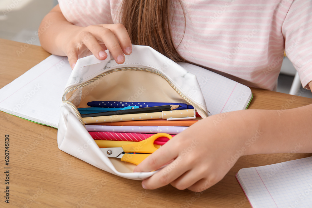 Little girl with pencil case at table, closeup