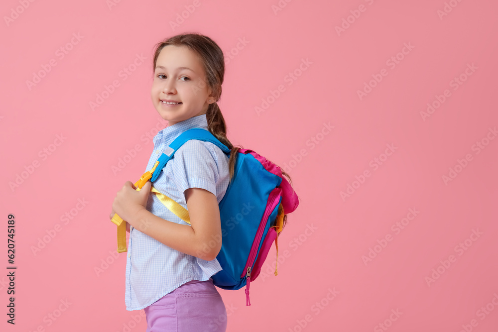 Little girl with backpack on pink background