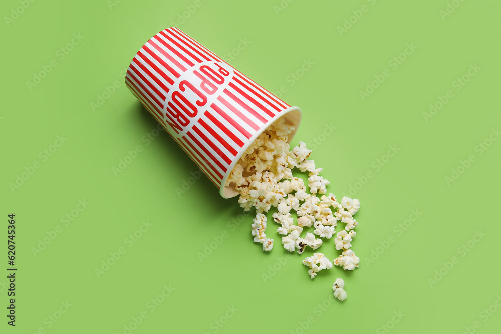 Bucket with tasty popcorn on green background