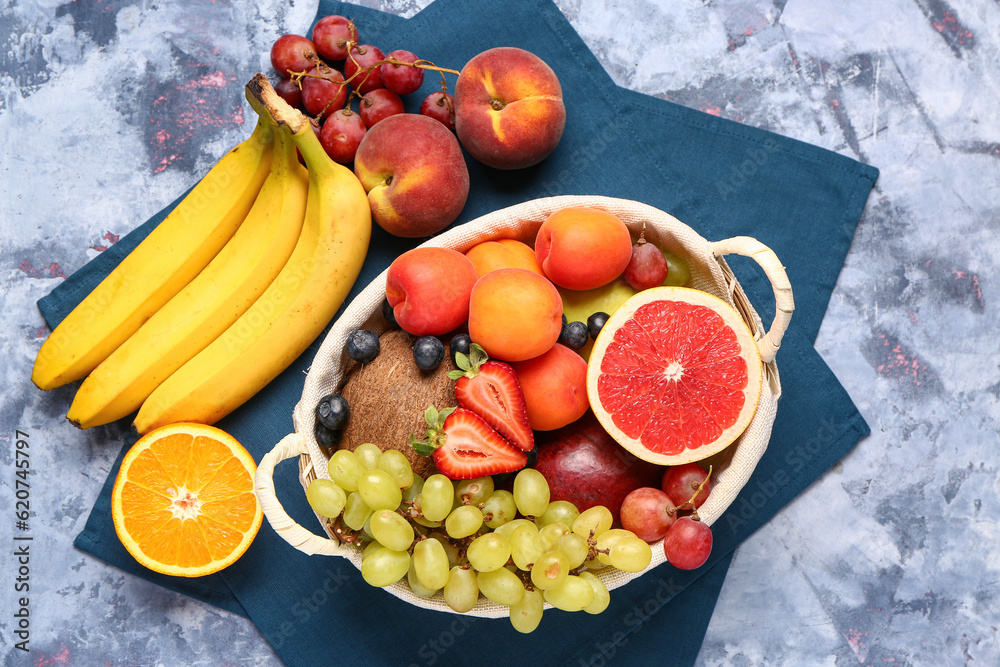 Wicker basket with different fresh fruits on blue background