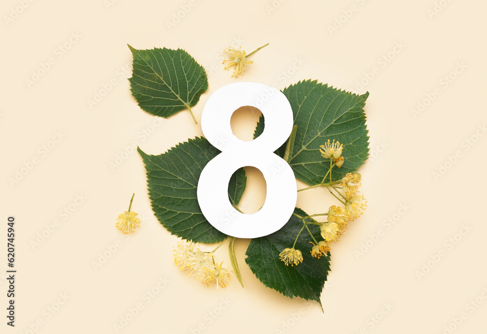 Linden green leaves and flowers with paper number eight on beige background