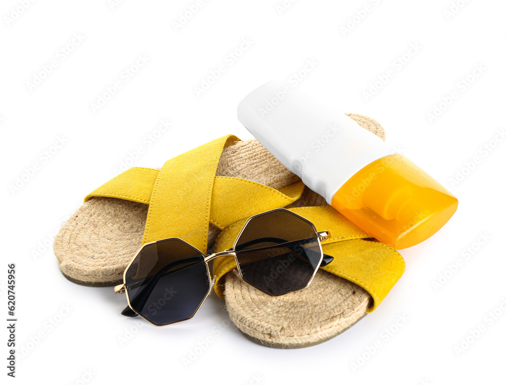 Flip flops with sunglasses and bottle of sunscreen cream isolated on white background