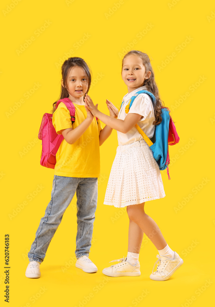 Little schoolgirls on yellow background