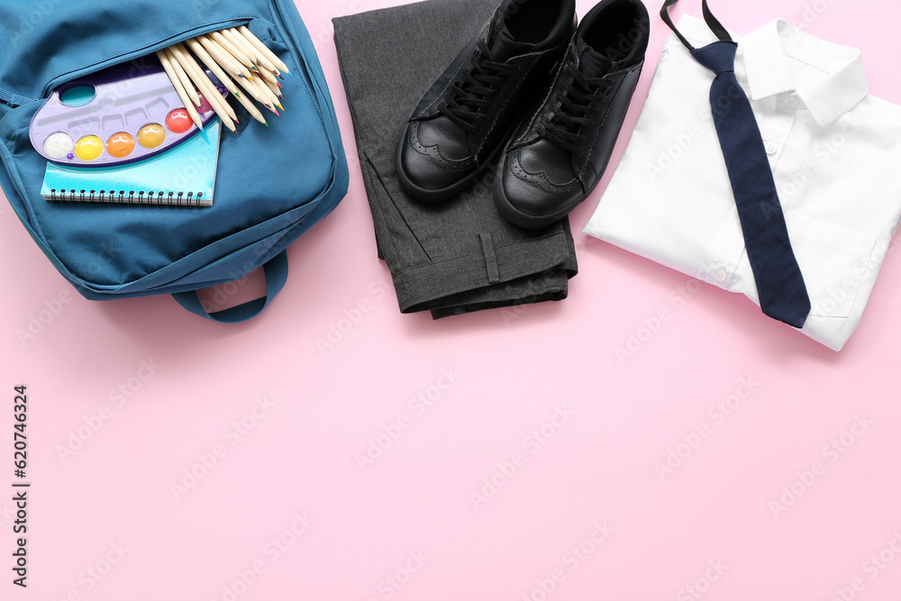 Stylish school uniform with backpack and stationery on pink background