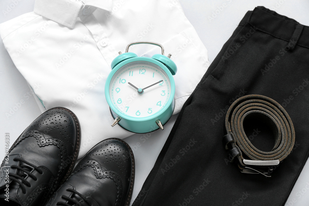 Texture of stylish school uniform with alarm clock as background