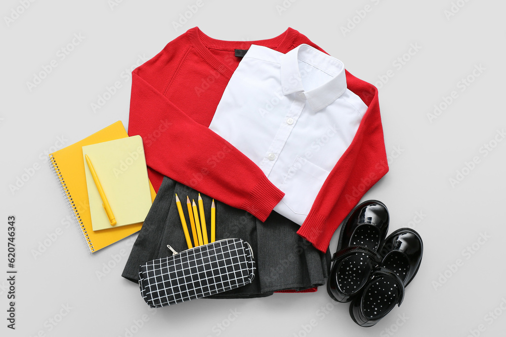 Stylish school uniform with different stationery on grey background