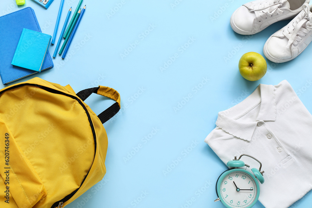 Stylish school uniform with fresh apple, backpack and stationery on blue background