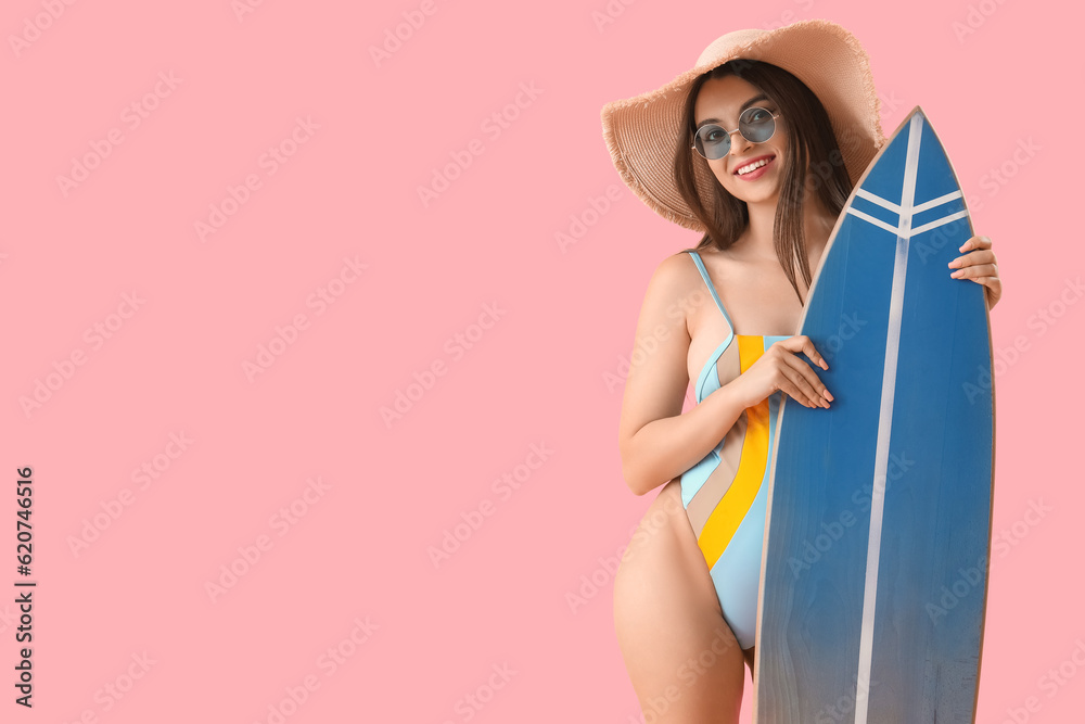 Young woman with surfboard on pink background