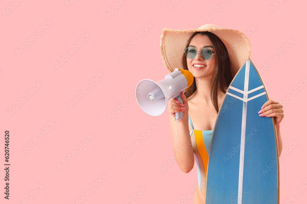 Young woman with surfboard and megaphone on pink background