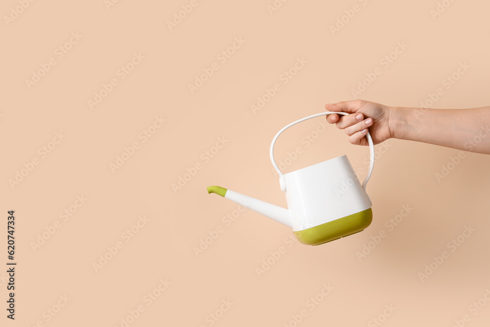 Gardener with watering can on beige background