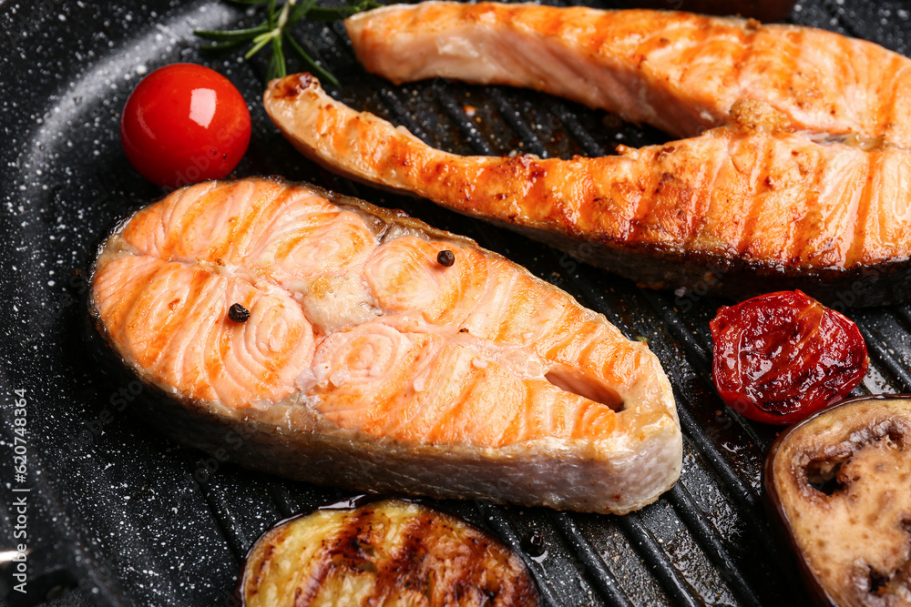 Tasty grilled salmon steaks in frying pan, closeup