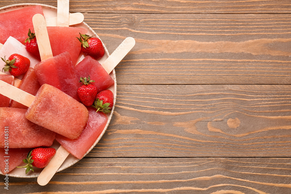 Plate with sweet strawberry ice-cream popsicles on wooden background