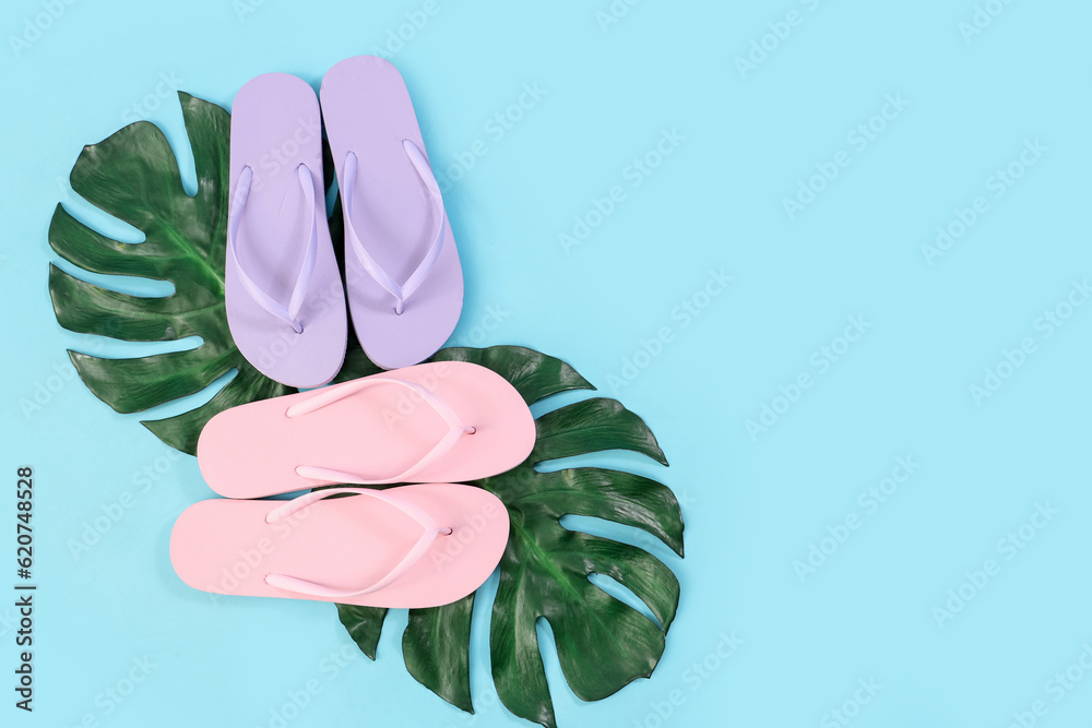 Flip-flops and tropical leaves on blue background