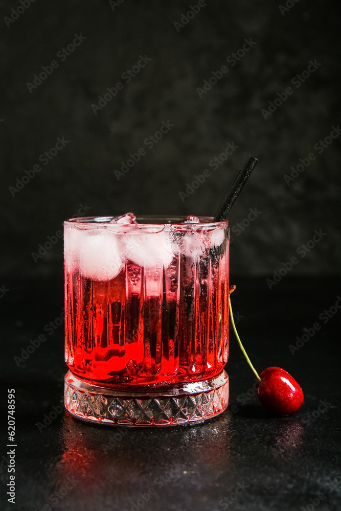 Glass of tasty cherry lemonade on black background