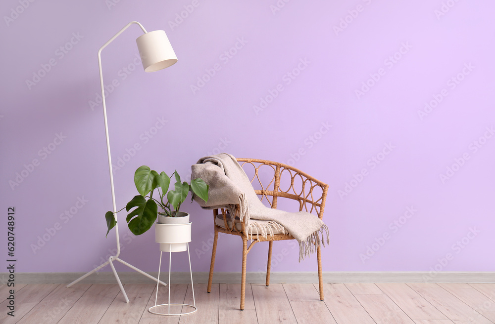 Armchair, lamp and houseplant near lilac wall