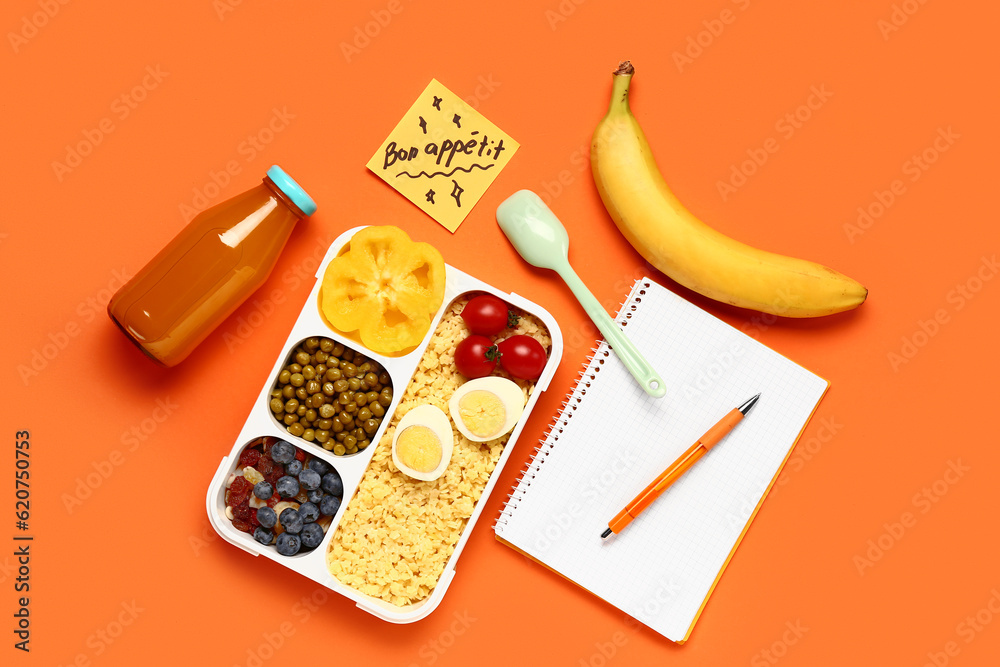 Stationery, tasty food in lunchbox and sticky note with text BON APPETIT on orange background