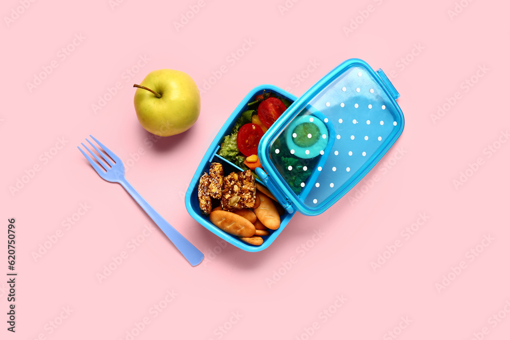 Apple, fork and lunchbox with tasty food on pink background