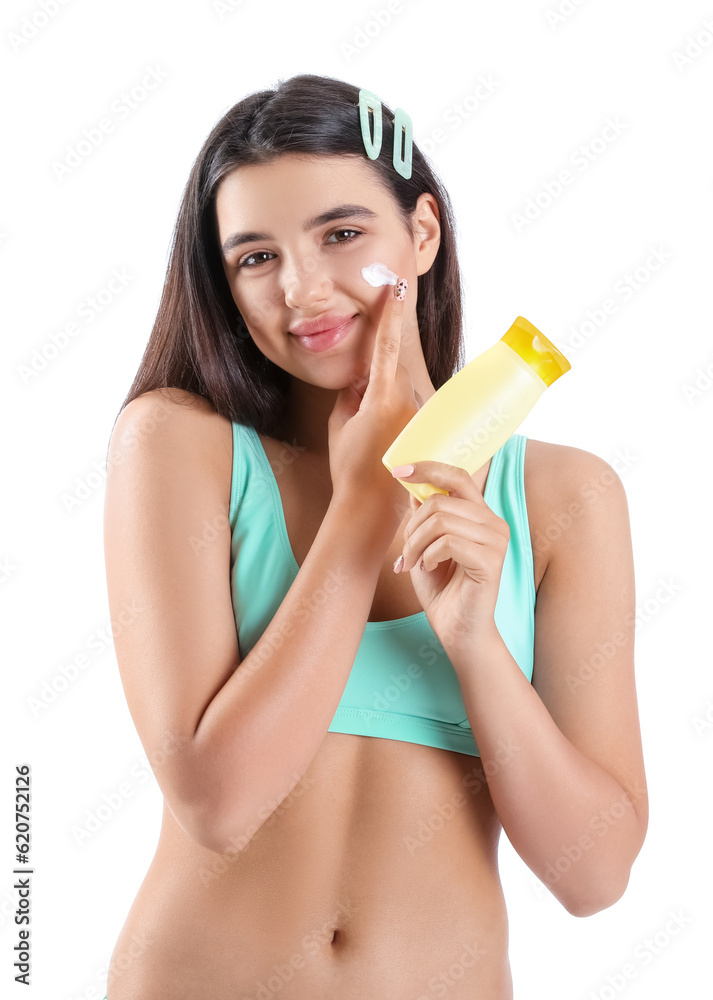 Beautiful young woman applying sunscreen cream on white background