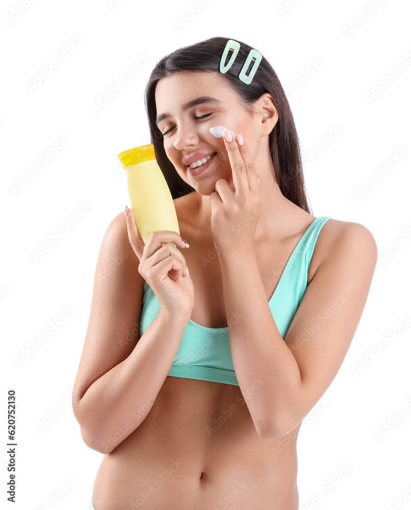 Beautiful young woman applying sunscreen cream on white background