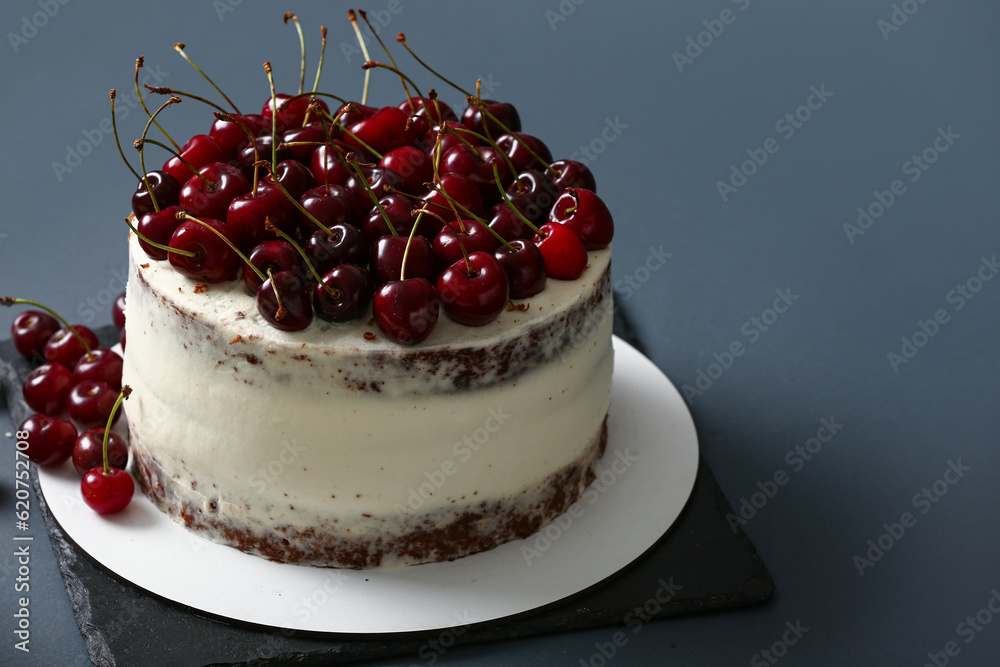 Board with tasty cherry cake on dark background