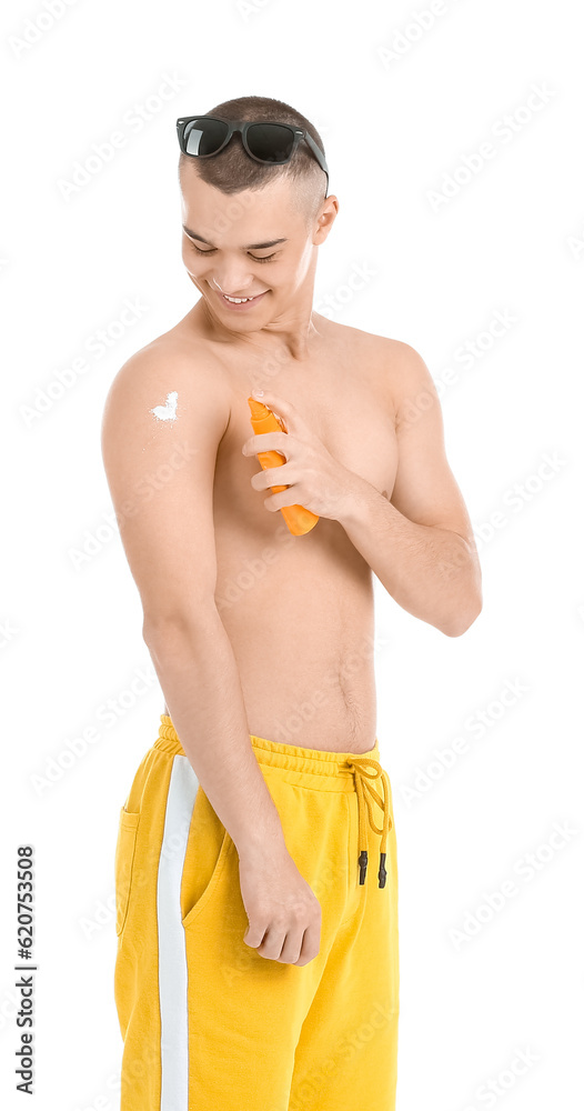 Happy young man in sunglasses applying sunscreen cream isolated on white background