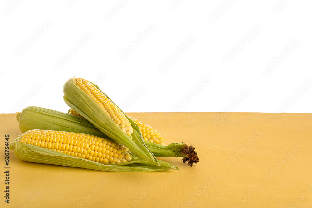 Fresh corn cobs on yellow table against white background