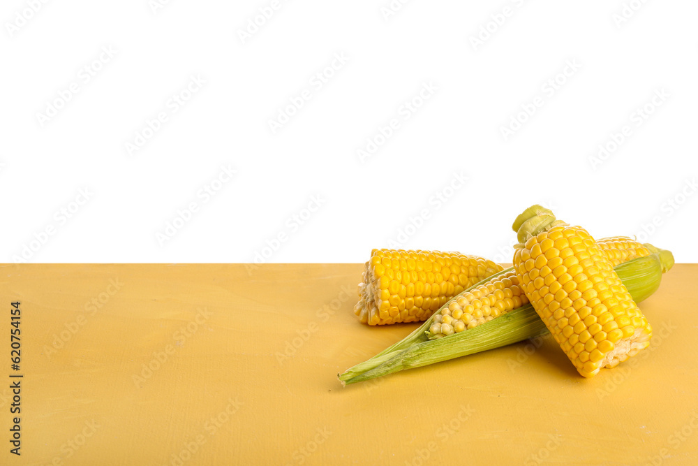 Fresh corn cobs on yellow table against white background