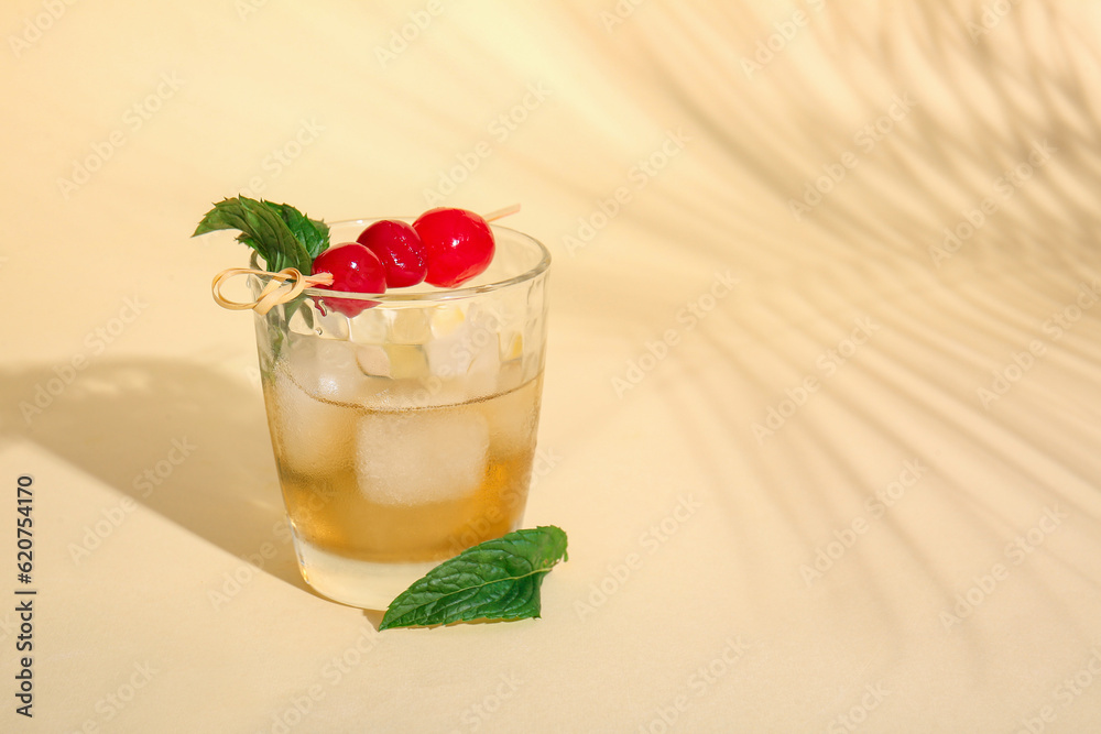 Glass of tasty cocktail with maraschino cherries on yellow background