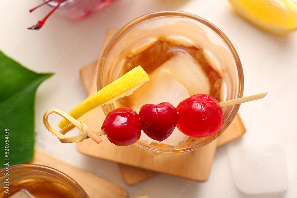 Glass of tasty cocktail with maraschino cherries on white background