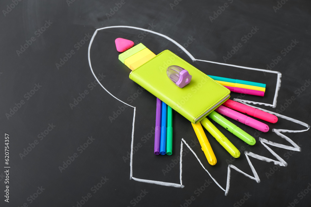 Drawn rocket with stationery on black background