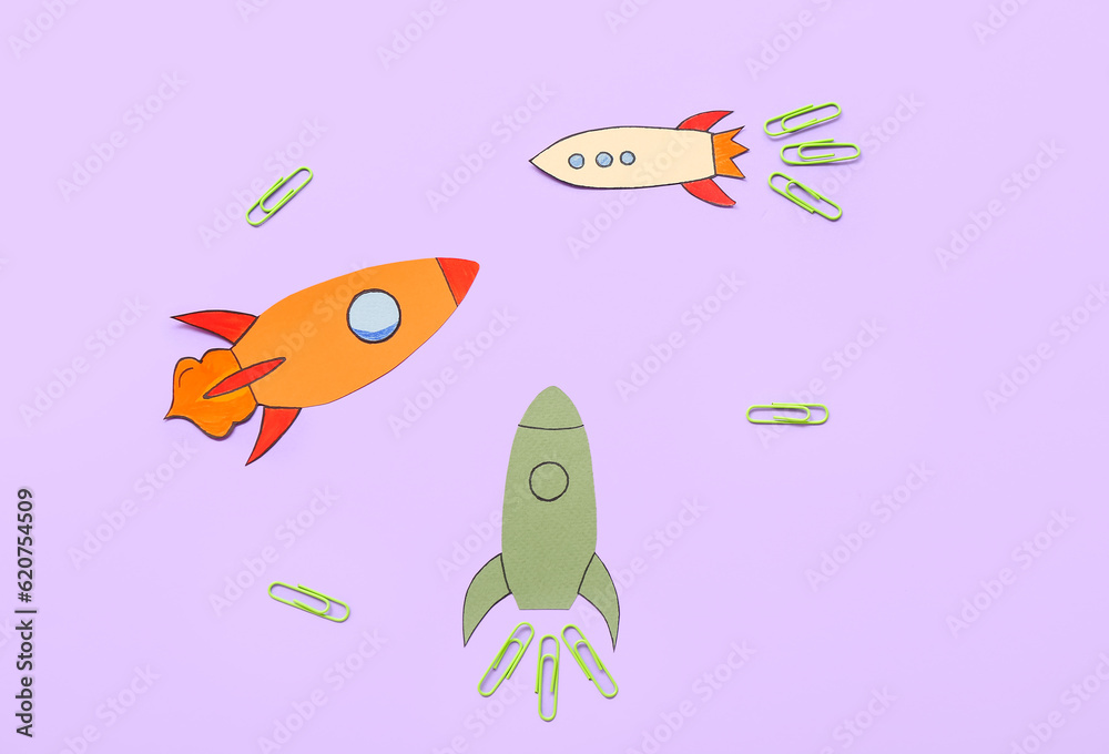 Paper rockets with clips on purple background