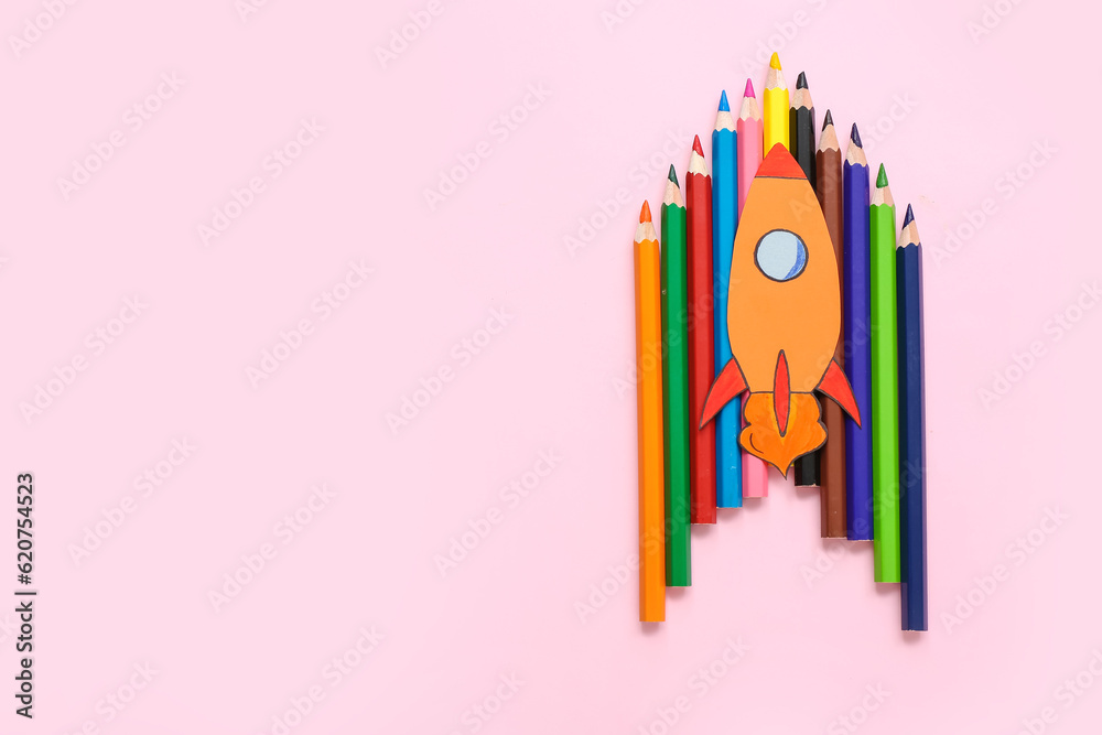 Pencils with paper rocket on pink background