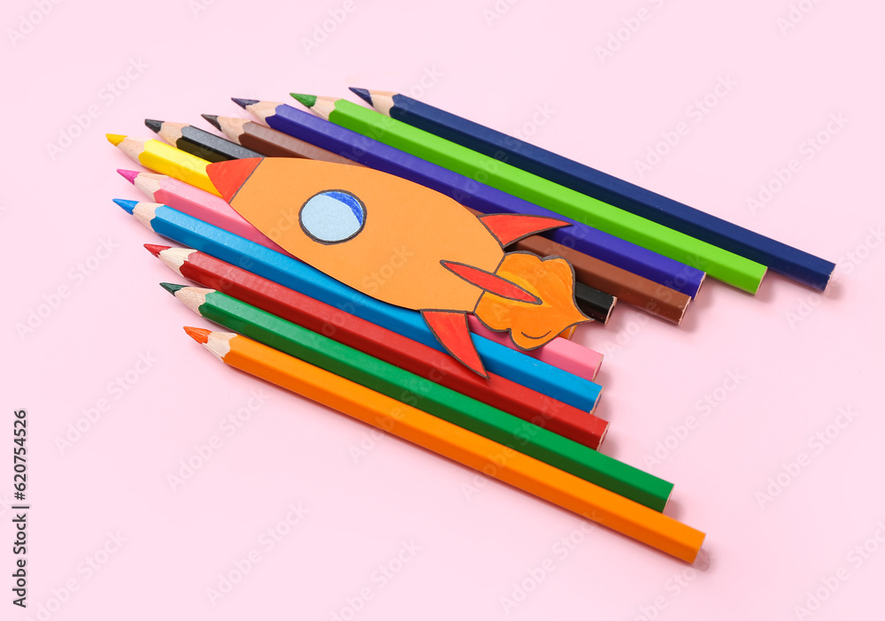 Pencils with paper rocket on pink background