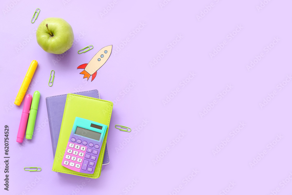 Paper rocket with school stationery and apple on purple background