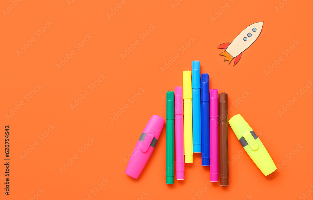 Markers with paper rocket on red background