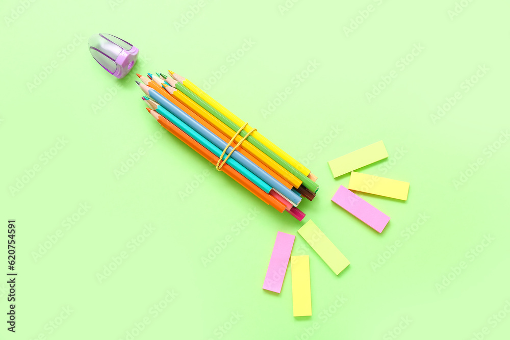 Rocket made of stationery on green background