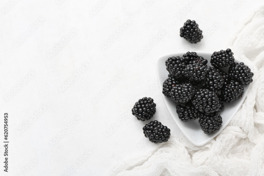 Plate with fresh blackberry on light background