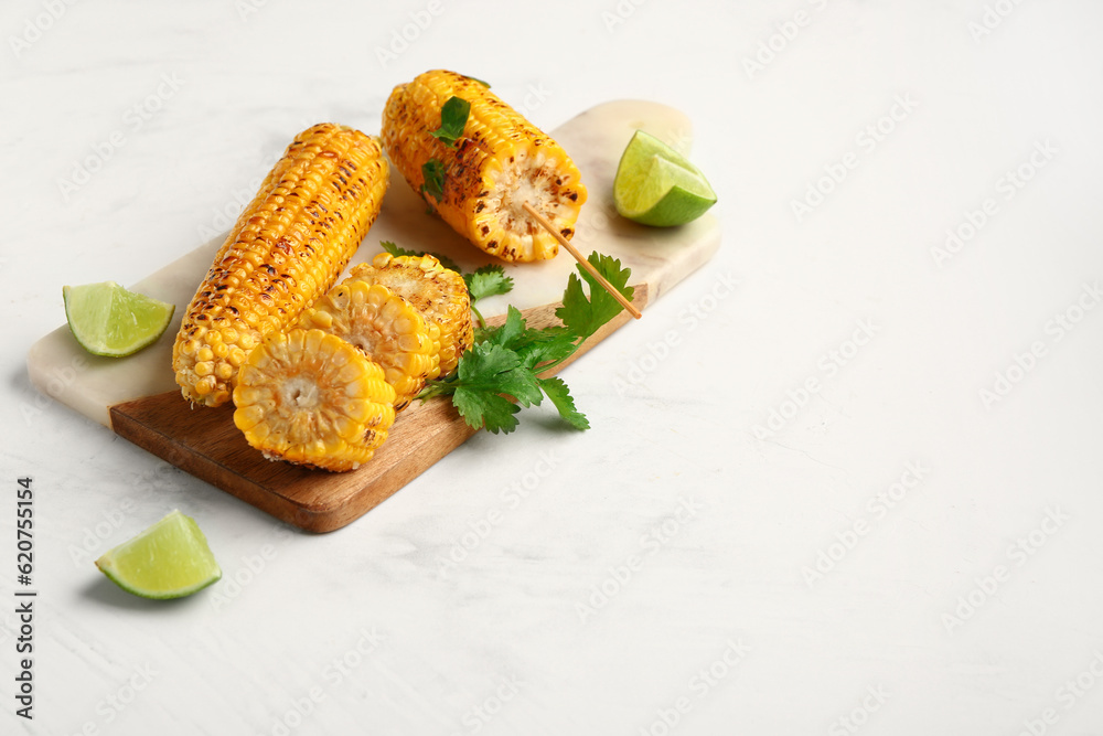 Board with tasty grilled corn cobs and parsley on white background