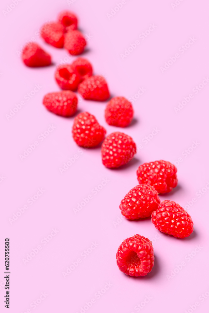 Many fresh raspberries on pink background