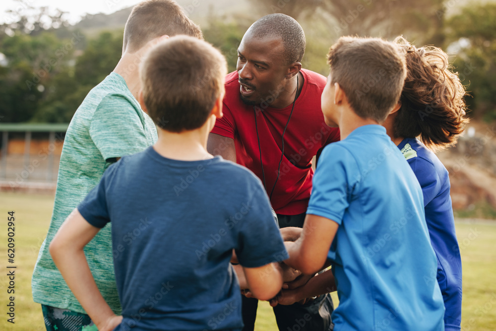 Male coach having a huddle with his school rugby team