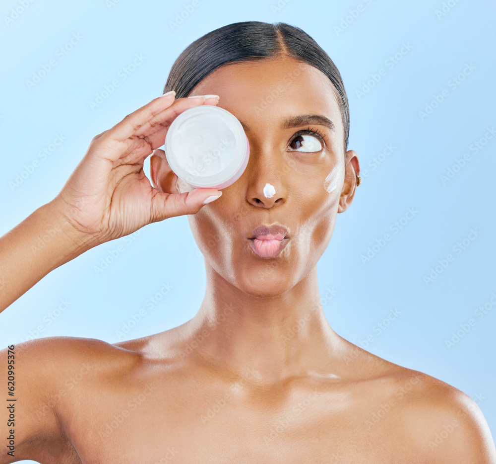 Woman, face and cream jar in studio, blue background and cosmetics with kiss emoji. Indian female mo