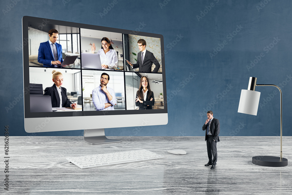 Attractive young european businessman standing on wooden desk with computer monitor on call with col