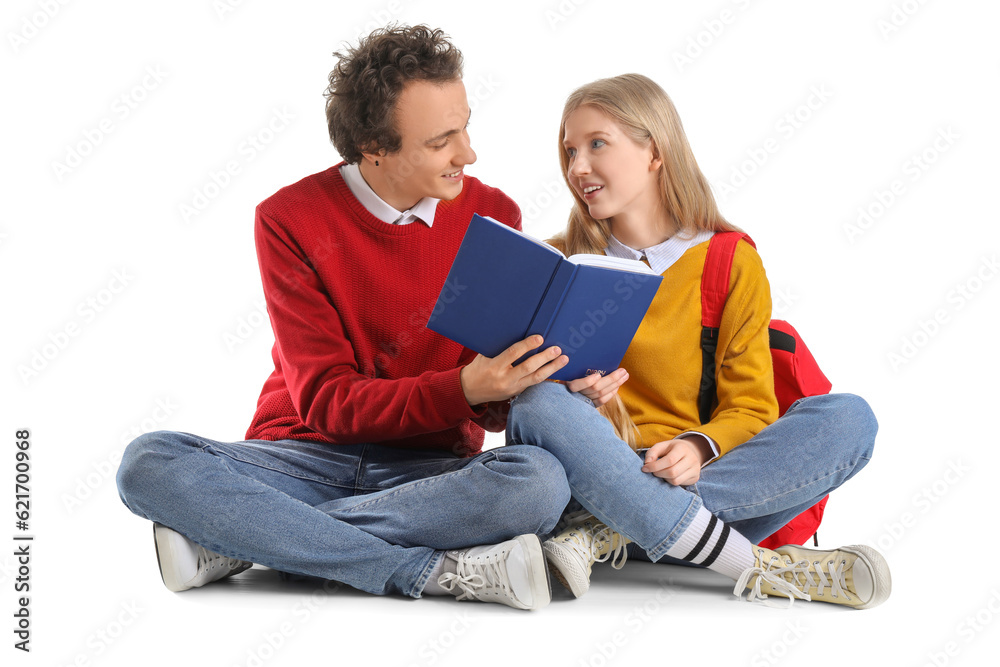 Teenage couple reading book on white background