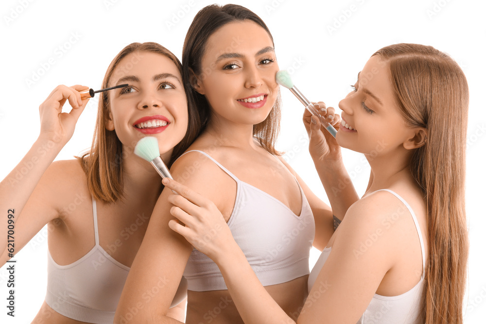 Young women with makeup brushes on white background