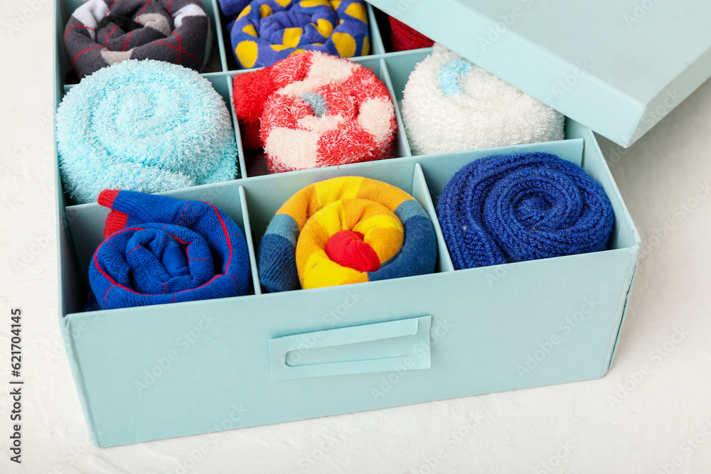 Box with different socks on light background, closeup